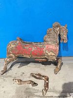 full view of carved wood carousel horse body with two legs detached on floor