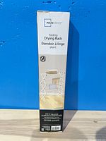 Front of sealed box showing Mainstays Folding Drying Rack