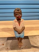 Full view of heavy painted seated boy figurine