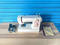 Full view of sewing machine with cord and paperwork