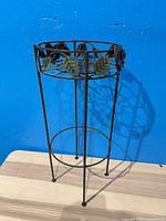 full view of metal plant stand showing decorative leaves and structure