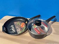 Two new pans: Cucina non-stick fry pan and GoodCook non-stick saucepan with lid, shown with retail packaging inserts