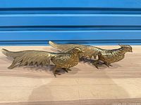 Both brass peacock figurines side by side showing full length and tails