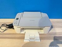 Top and front view of white Canon Pixma printer with attached power adapter lead visible