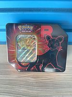 Front view of Team Rocket Pokemon tin showing Persian artwork and holographic card in window