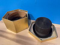 Black velvet riding top hat set in opened hexagonal gold box