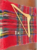 Creagaran label on red plaid mohair scarf with wooden hanger on top