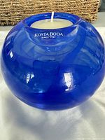 Angled front view of cobalt blue Kosta Boda Atoll glass votive with candle inserted