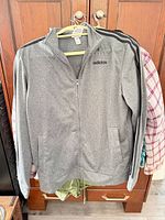 Front view of Adidas grey full-zip jacket with logo and black stripes