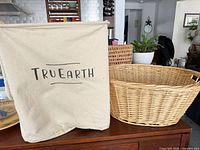 Front view of Tru Earth canvas hamper beside wicker basket