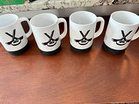 Four identical Tim Hortons hockey mugs on table