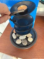 Fountain partially assembled showing tiered bowls and river stones