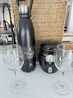 Group shot of insulated bottle, coffee canister and two wine glasses