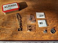 Overview showing Altoids tin, bracelet, earrings bag and loose charms