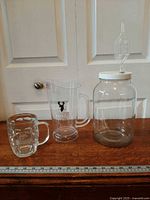 All three items: fermentation jar with lid/airlock, plastic pitcher, glass mug beside ruler for scale