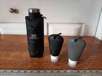 Water bottle and two travel bottles side by side with ruler for scale