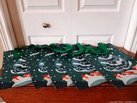 Five green Christmas tree gift bags laid out to show fronts and handles