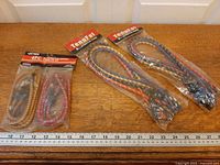 Three sealed packages of bungee cords on ruler for scale