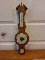 Full view of wooden banjo barometer with thermometer and hygrometer