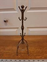Full view of brass miniature coat rack style stand with hooks and base
