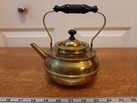 Left-front view showing brass body, spout, handle, lid, and scale for size