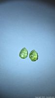 Pair of lemon-lime green leaf-carved tourmalines on white background