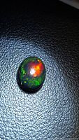Front view of oval cabochon Ethiopian black opal showing multicolor play of color