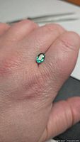 Emerald on finger showing size and color