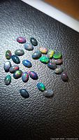 Loose oval Ethiopian black opals on black surface