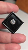 Front view of loose round brilliant cut moissanite in black display box