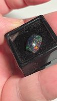 Opal in display box showing vivid green, red, orange flash