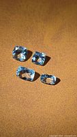 Four pale blue aquamarine gemstones on brown background