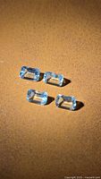 Four emerald-cut aquamarine gemstones on brown background