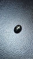 Front view of oval black star diopside showing four-ray star effect