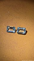 Pair of rectangular light blue aquamarines on brown background