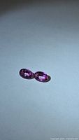 Two oval pink gemstones on neutral background