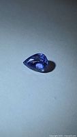 Pear cut violet-blue tanzanite loose stone on neutral background