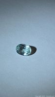 Oval-cut seafoam blue gemstone on neutral background