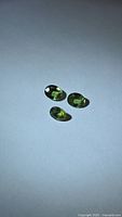 Three oval green sapphires on white background