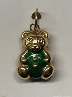 Front view of 18K gold teddy bear pendant with green enamel belly
