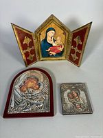 All three religious pieces displayed: Florentine triptych open, arched plaque, sterling plaque