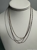 Four layered sterling silver chains on display bust