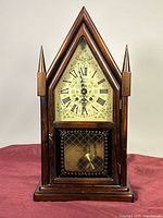 Front view of wood steeple mantel clock showing dial and lower door
