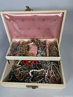 Jewelry box open showing top tray and bottom filled with assorted jewelry