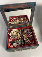 open wooden jewelry box with visible costume jewelry assortment