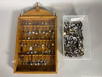 Wooden display cabinet beside bin of loose collector spoons