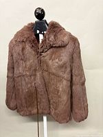 Front view of brown rabbit fur jacket on stand