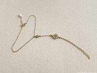Full view of gold filled chain bracelet showing eye charm, slider bead, clasp and dangle