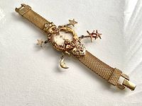 Full view of gold-tone Kirks Folly charm watch with mesh band and charms
