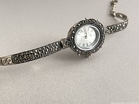 Close view of watch showing oval dial, marcasite bezel, bracelet detail